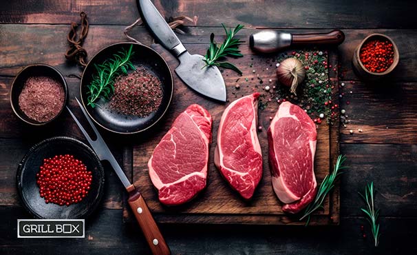 Cortes finos de carne sobre tabla de madera y equipo para asar