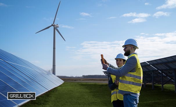 Hombre y mujer cerca de turbina eólica y paneles solares