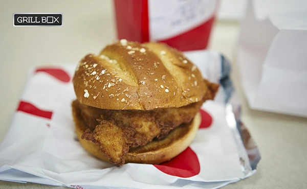 Hamburguesa de pollo rostizado servida sobre una bandeja de cartón